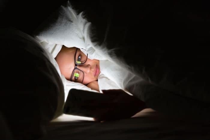 Woman looking at phone in her bed